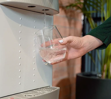 Vaso siendo llenado con agua filtrada desde dispensador Culligan en oficina