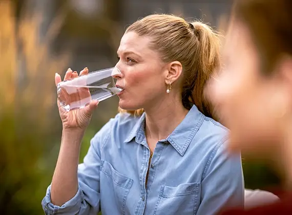 Mujer disfrutando un vaso de agua purificada Culligan al aire libre