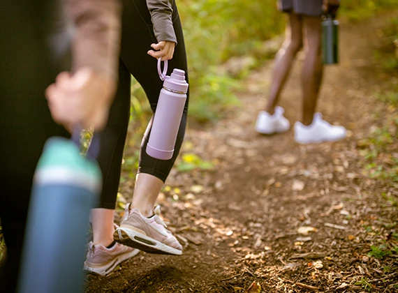 Personas caminando por sendero con botellas reutilizables llenas de agua purificada 